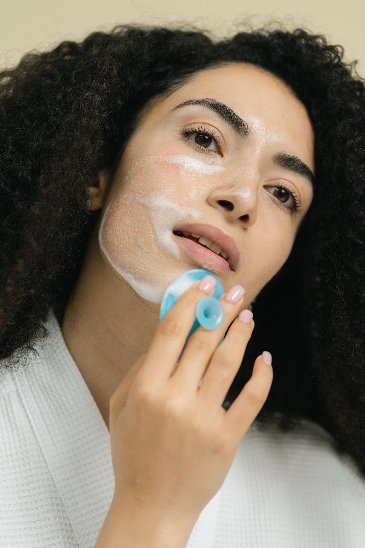 Woman cleansing her face with a silicone facial cleansing brush
