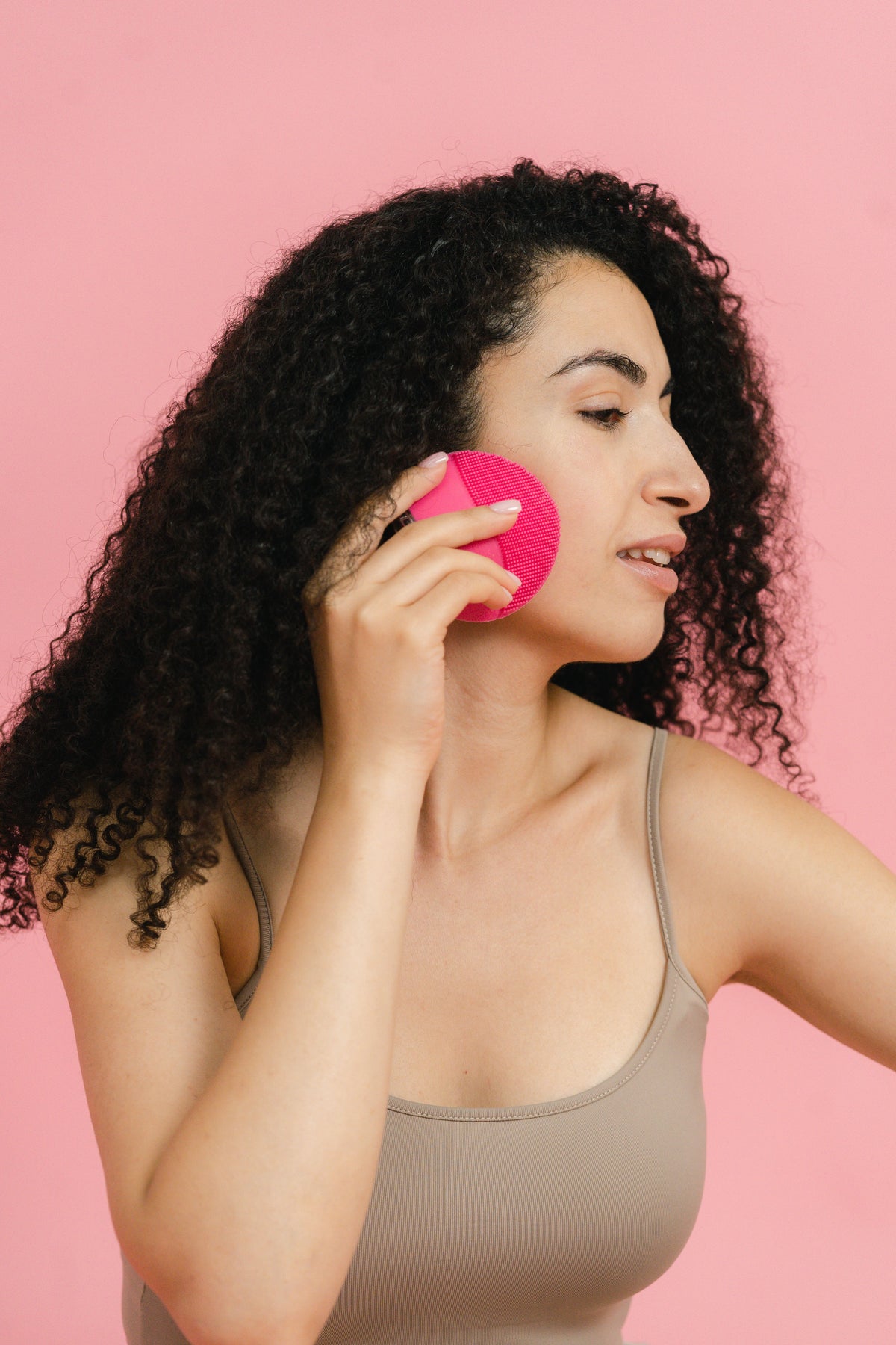 Pink silicone facial cleansing brush held up close