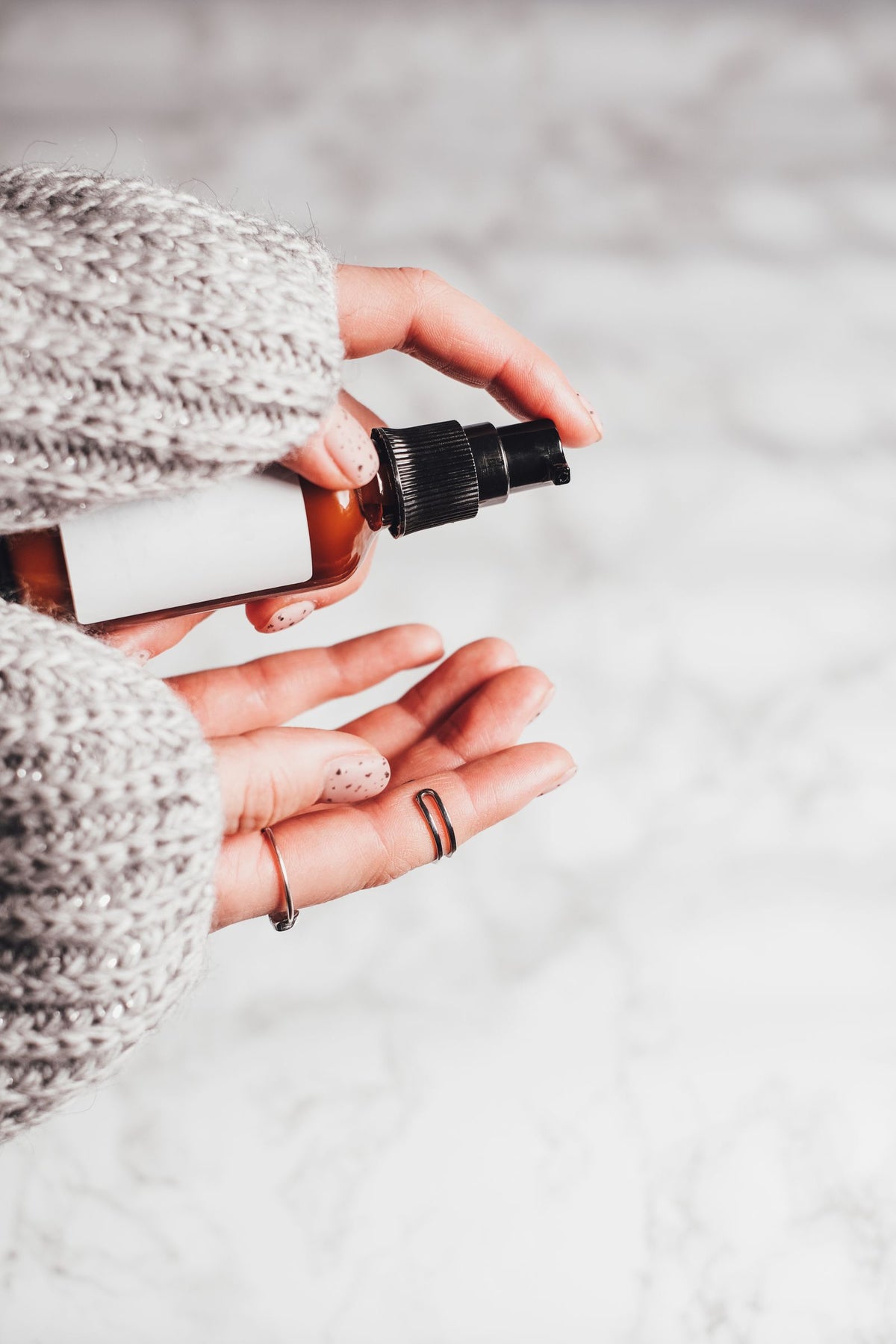 Hand applying facial mist spray