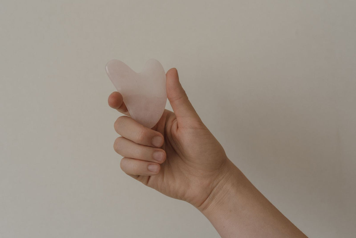 Hand holding rose quartz gua sha tool