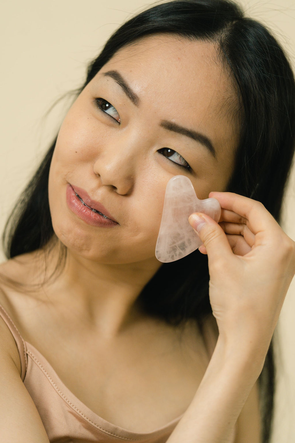 Woman performing facial massage with gua sha tool