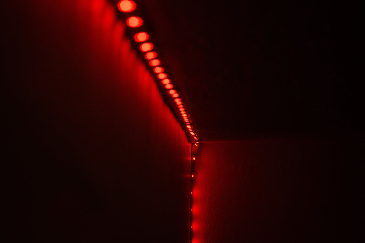 RGB LED strip light installed along a wall glowing red