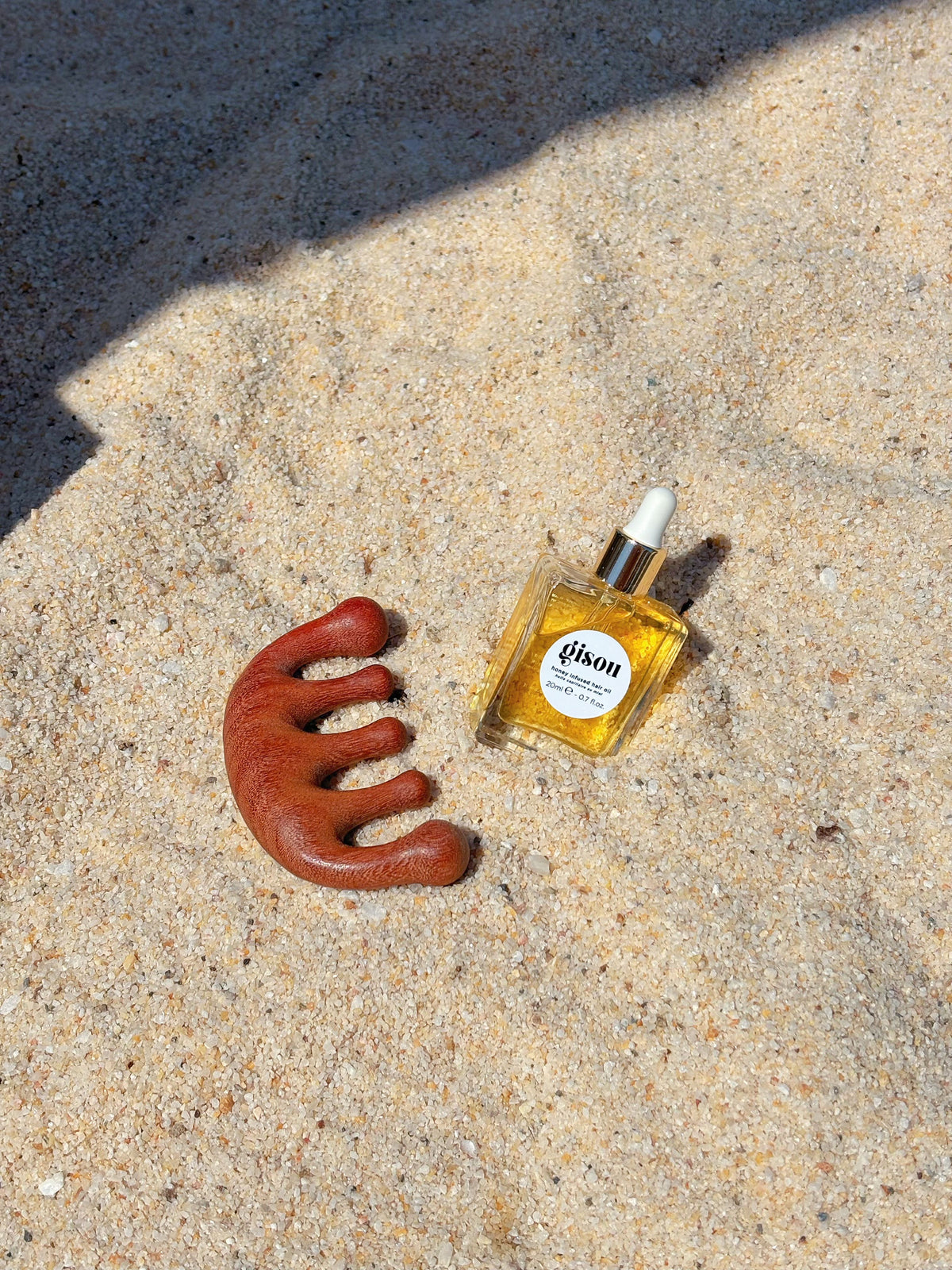 Silicone scalp massager brush beside a bottle of hair oil
