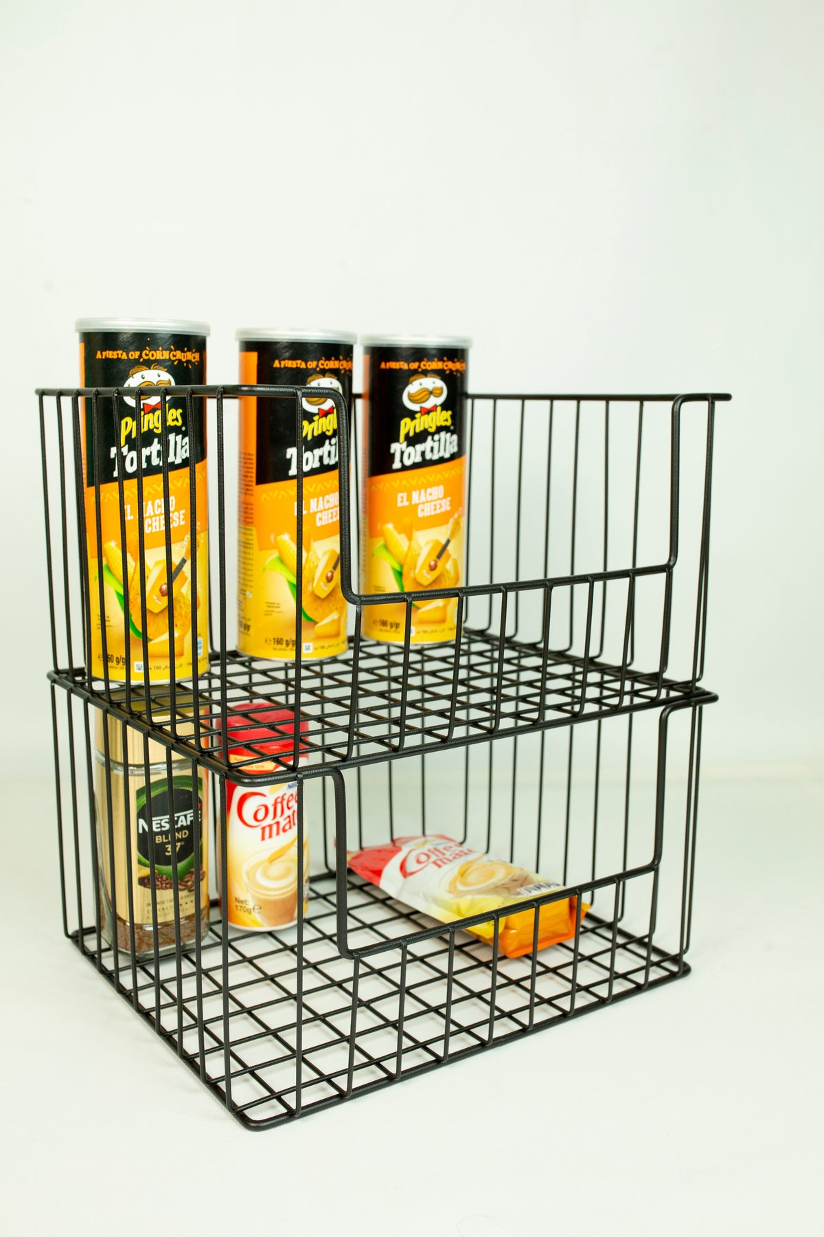 Metal wire storage basket on a pantry shelf holding snacks and cans