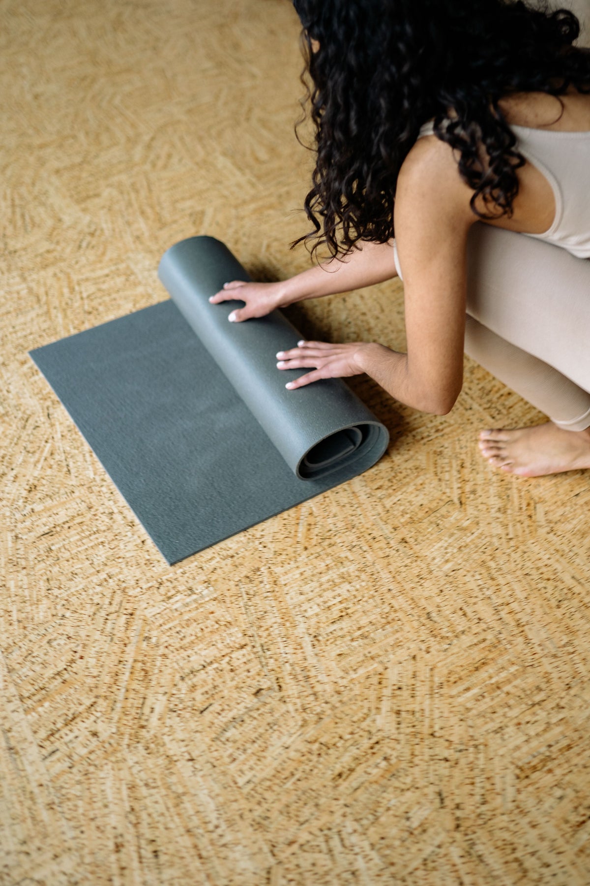 Woman rolling out a non-slip yoga mat on a wooden floor