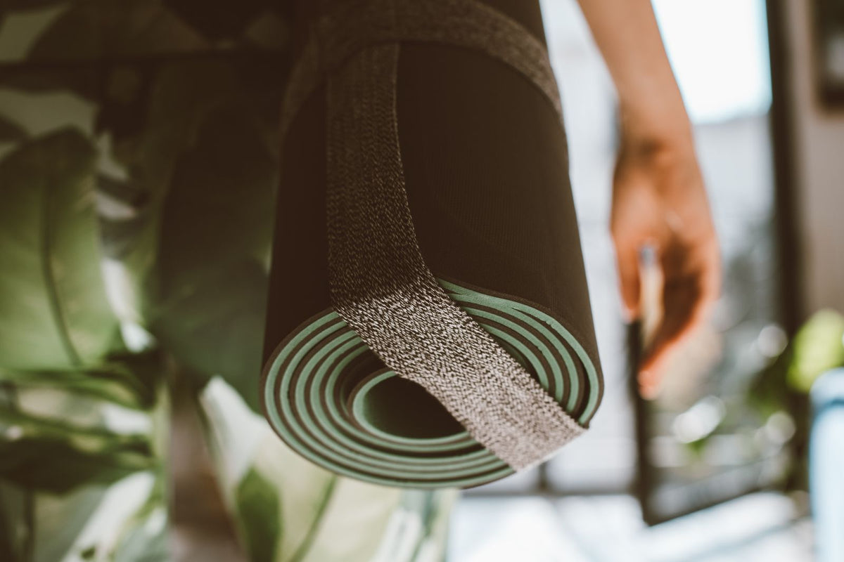 Rolled non-slip yoga mat secured with its carry strap